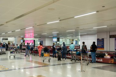 Delhi, Hindistan - 30 Mart 2023: Indira Gandhi Uluslararası Havaalanı 'nın varış bölgesinde bagaj teslim bantları bekleyen insanlar