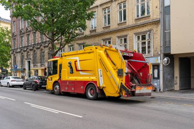 Kopenhag, Danimarka - 30 Haziran 2023 Kopenhag sokaklarında büyük sarı ve kırmızı bir çöp kamyonu.