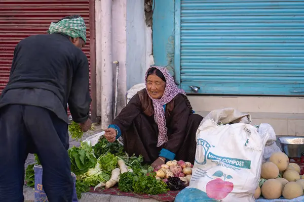 Leh, Hindistan - 12 Eylül 2024: Bir sebze satıcısı tarihi şehir merkezinde bir müşteriye hizmet veriyor