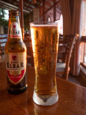 Berat - Arnavutluk, Eylül, 3 2021 - Bir barın masasında cam ve şişe Elbar birası