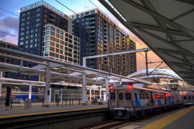H.D.R. image of three light rail trains preparing for departure from Denver's Union Station. With apartment buildings in the background and a peaceful sunset during the golden hour.