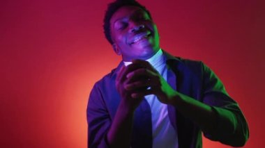 Parti ilham kaynağı. Neon insanları. Pozitif enerji. Renkli lambayla eğlenen rahat adam kırmızı ışık gradyan arka planında dans edip şarkı söylüyor..