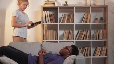 Öğrenciler yorulur. Evde öğrenim. Uykusuzluk muayenesi. Umursayan kız uyanıyor yorgun tembel arkadaşı oturma odasındaki kanepede uyukluyor..