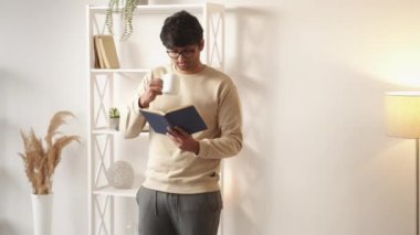 Evde rahatla. Okuyan adam. Eğlencenin tadını çıkarıyorum. Gülümseyen sıradan bir adam elinde kitapla kahve içiyor..