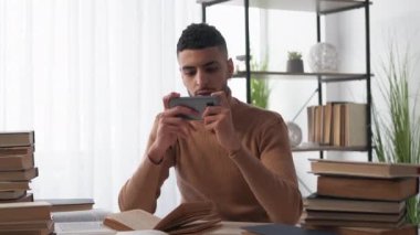 Oyun bağımlılığı. Erkek öğrenci. Kazanan heyecan. Onun yerine aydınlatma odasındaki kitaplarla masa başında oturup akıllı telefondan oynayan mutlu bir adam..