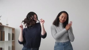 Mutlu arkadaşlar. Dans eden kadınlar. Ev kutlamaları. Neşeli kadınlar ışık odasının içinde müzikle birlikte hareket ediyorlar..