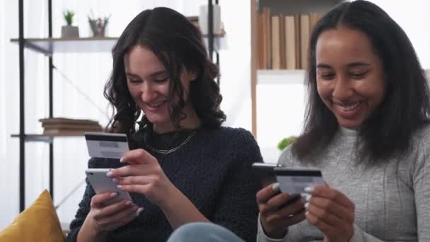 网上支付 快乐的女人移动操作 笑着打智能手机的女性朋友拿着信用卡坐在灯光房里 — 图库视频影像