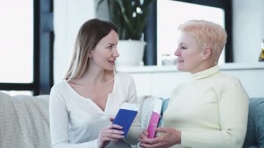 Seyahat planı. Aile ilişkisi. Tatil ilhamı. Mutlu kız ve anne kanepede oturup, ellerinde pasaport biletleriyle gelecek yolculuklarını tartışıyor..