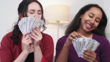 Para sevinci. Heyecanlı kadınlar. Zenginlik duyguları. Gülümseyen hayalperest bayan arkadaşlar mutluluklarını ifade ediyorlar. Işıklı odanın içinde dolarların kokusunu tutuyorlar..