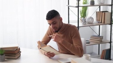 Uzaktan eğitim. İlham verici bir adam. Çalışma süreci. İlginç kitaplar okuyan mutlu bir adam aydınlatma odasının iç tarafında oturup notlar alıyor..