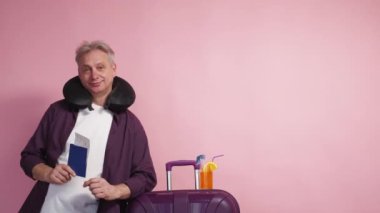 Tatil seyahati. Tatmin olmuş bir adam. Reklam arkaplanı. Pembe fotokopi alanında pasaport biletleriyle poz veren orta yaşlı mutlu bir adam..