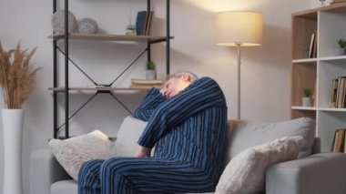 Tembel bir sabah. Uykulu adam. Ev tatili. Pijamalı, orta yaşlı bir erkek rahat bir kanepede uyanıyor..