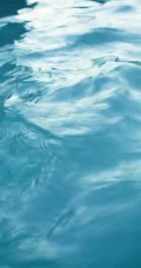 Dikey video. Su yüzeyi arka planı. Dalgalanma dokusu. Su tazeliği. Mavi renk saf deniz dalgaları ışık yansıması ile hareket ediyor. RED Sinema Kamerasında Çekim.