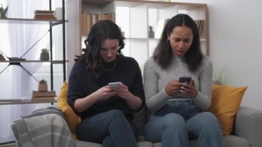 Etkileyici bir sevinç. Şaşırmış kadınlar. Gezici piyango. Sanal galibiyette heyecanlanan iki kadını şok etti. Elinde akıllı telefon, kanepede, aydınlatma odasının içinde oturuyor..