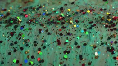 Şenlik arka planı. Akışkan sanat. Soyut resim. Renkli çıngıraklı yeşil sıvı boya makroda yüzüyor ve ağır çekimde ateş ediyor..