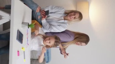 Dikey video. Aile ilişkisi. Dijital bağımlılık. Kadın nesli. Annem selfie çekerken, mutlu kız işaretleri çiziyor. Anneanne akıllı telefon aydınlatma odasının içini kaydırıyor..