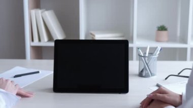 Online sunum. Video toplantısı. Başarı kutlaması. Tanımlanamayan bayan meslektaşlar iş yerinde siyah model ekran tabletleriyle alkışlıyorlar..