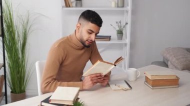 İlham verici bir eğitim. Erkek öğrenci. İlginç bir kitap. Bir fincan kahve ve aydınlatma odasında kitap okuyan mutlu sıradan bir adam..