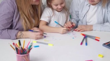 Aile zamanı. Sanat yaratıcılığı. - Kadın ilişkisi. Sevimli küçük kız ışık odasının iç tarafında renkli kalemlerle çizim yapmaktan zevk alıyor..