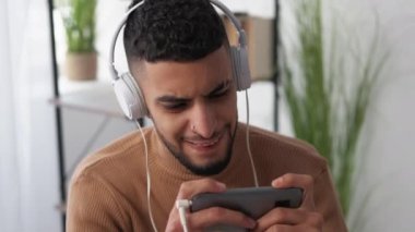 Sanal gerçeklik. Oyuncu adam. İlgisiz eğitim. Kulaklıklı sıradan bir adam aydınlatma odasındaki kitaplarla akıllı telefon oynuyor..