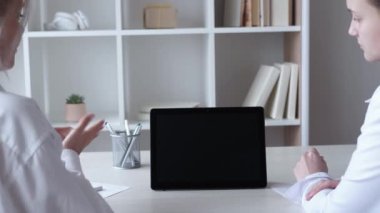 İnternetteki konferans. Dijital toplantı. Mesafe brifingi. İş kadınları ofis içinde siyah boş ekranlı tablet kullanarak projeyi tartışıyor.