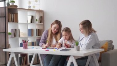 Aile tablosu. Keyif alıyorum. Yaratıcı sanat. Annesi ve büyükannesiyle çizim yapan küçük mutlu bir kız..