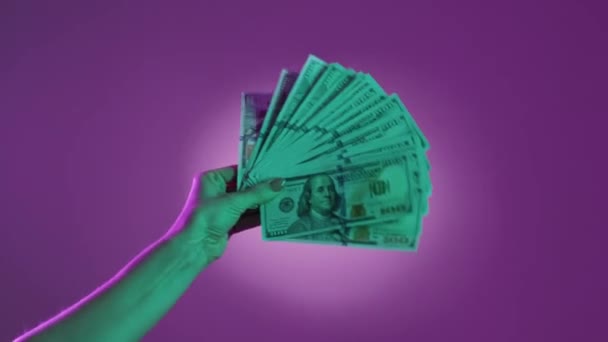 財務上の成功 金持ちだ お金を使う キャッシュドルのファンと握手ネオンライトパープルグリーンの背景 — ストック動画