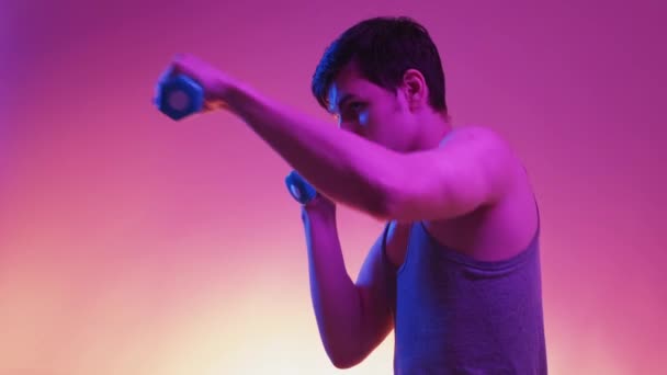스포츠 라이트 초상화 근육질의 남자가 보라색 배경에 만두를 가지고 싸우는 — 비디오