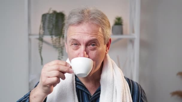 朝のコーヒー 幸せな老人だ さわやかな一日 明るいバスルームのインテリアでテスティードリンクを楽しむ正の年上の男性 — ストック動画