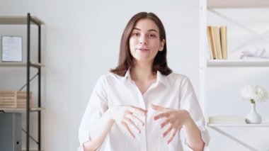 Çevrimiçi görüşme. Uzaktan konferans. Mesafe iletişimi. Kendine güvenen neşeli iş kadını modern ofis içinde el sallayarak selam veriyor. Uzun video çekimi.