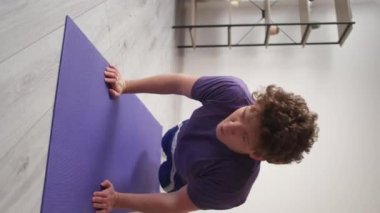 Dikey video. Evde eğitim. Güçlü bir adam. Sağlıklı aktivite. Aydınlık odada yoga minderi üzerinde şınav çeken sıradan bir adam..