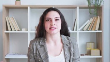 Çevrimiçi görüşme. Uzaktan konferans. Mesafe iletişimi. Kendine güvenen neşeli iş kadını modern ofis içinde el sallayarak selam veriyor. Uzun video çekimi.