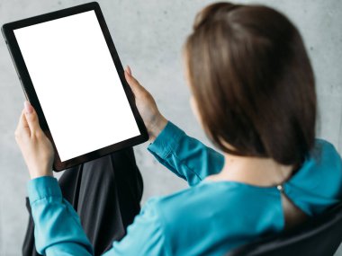 Ofis işleri. Bilgisayar modellemesi. Dijital teknoloji. Tanımlanamayan kadın elinde tablet bilgisayarla boş ekran lambasının iç tarafında oturuyor..