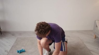 Ev sporu. İlham verici bir adam. Sanal eğitim. Halter egzersizi yapan sıradan bir adam. Düz konumda dizüstü bilgisayara bakıyor. İç mekânda..