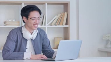 Çevrimiçi tercüman. Sanal arama. Uzaktan antrenörlük konferansı. Duyarlı, kulaklıklı akıllı adam hafif modern ofis içi bilgisayarını kullanarak konuşuyor. Uzun video çekimi.