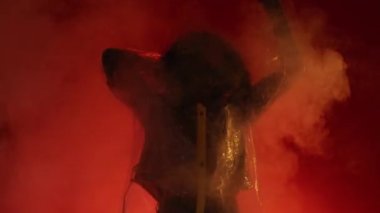 Gece kulübü partisi. Heyecanlı kadın. Siber punk modası. Güneş gözlüklü, yağmurluklu, dans eden mutlu şık bayan kırmızı, açık renkli, dumanlı bulutlar arka planda ağır çekim.