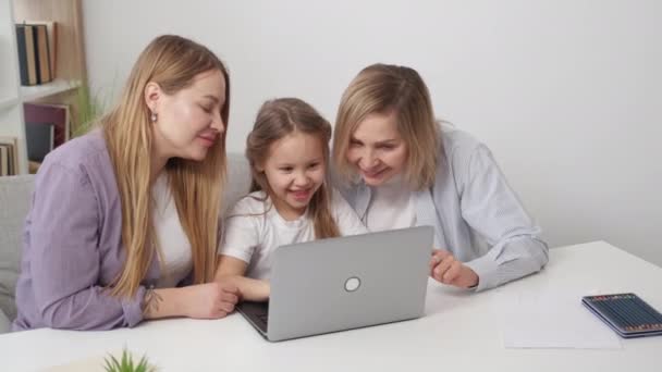 网络游戏 孩子们很好玩密切的家庭关系 快乐的女孩与支持她的母亲和祖母一起在笔记本电脑上玩耍 坐在明亮的室内 — 图库视频影像