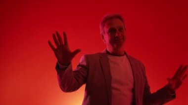 Hafta sonu eğlencesi. Mutlu yaşlı adam. Neon ışıklı portre. Kırmızı mavi yanıp sönen arka planda dans eden zeki, sıradan görünümlü son sınıf öğrencisi..