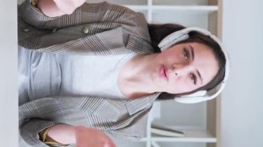 Dikey video. Sanal blog. Sosyal medya iletişimi. Mutlu kadın vlogger kulaklıkla selamlaşıp merhaba diyor. İçeriği kaydediyor..