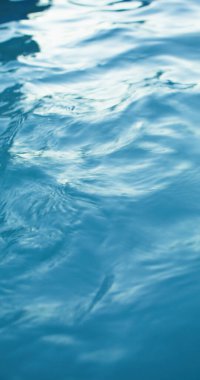 Su altyapısı. Dalga dokusu. Yüzme havuzu. Yaz tatili. Odaklanmamış mavi renk şeffaf temiz göl yüzeyinde ışık yansıması ile dalgalanır..