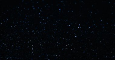 Parlak bir geçmişi var. Bokeh sim dokusu. Gece gökyüzü yıldızları. Odaklanmamış mavi renk ışık yansıması koyu siyah soyut serbest alan duvar kağıdı üzerinde.