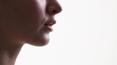 Kadın güzellik prosedürü. Siluet profil portresi. Reklam arkaplanı. Beyaz arkaplanda poz veren dolgun dudaklı, tensel tanınmayan kadın..