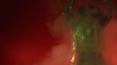 Parti eğlencesi. Odaklanamayan kadın. Neon ışıklı portre. Tanımlanamayan mutlu bayan kırmızı sarı ışıklı dumanlı bulutların üzerinde dans ediyor arka plan yavaş çekim bulanıklığı.