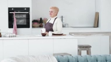 Ev fırını. Kadın tencere. Dinlenmenin tadını çıkarıyorum. Mutfak odasının içinde pişmiş kurabiyeleri beklerken çay içen mutlu, rahat, yaşlı kadın..