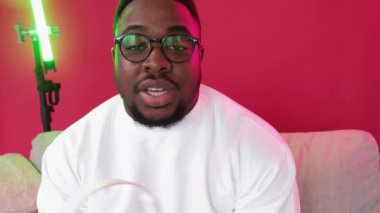 Gadget İnceleme Teknoloji Vlog 'u. Müzik aleti sunumu. Kendine güveni tam, etkili adam kulaklıkları test ediyor, video blogunu kırmızı koltukta kaydediyor..