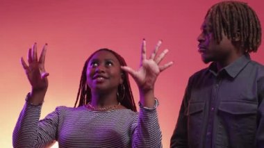 Farklı planlar. Yanlış anlaşılma. Neon ışıklı portre. Mor şeftali rengi arka planda kuşkucu, sevilen bir adama rüyaları ve dilekleri anlatan ilham veren siyah kadın..