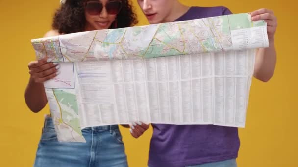 旅の興奮 幸せなカップル 休暇のツアー 好奇心が強い男と女喜びを感じる地図上の道の方向を選択黄色の背景に滞在 — ストック動画