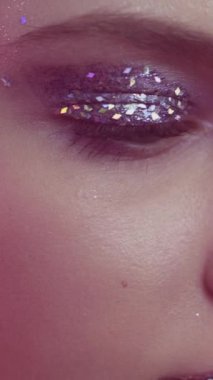 Dikey video. Parlak makyaj. Güzel surat. Disko görüntüsü. Kırmızı neon renkli parlak dudakları olan düşünceli kadın gözlerine yakın çekim..