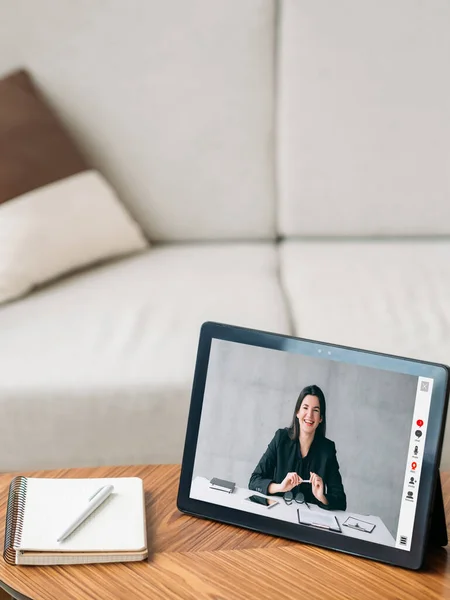 Video consulting. Web call. Remote conference. Cheerful female professional expert on tablet screen working online at couch home interior with free space.