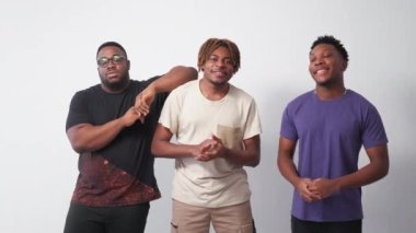 Happy black men. Friendly relationship. Model shooting. Positive hipster guys giving fist bump posing on light wall background.